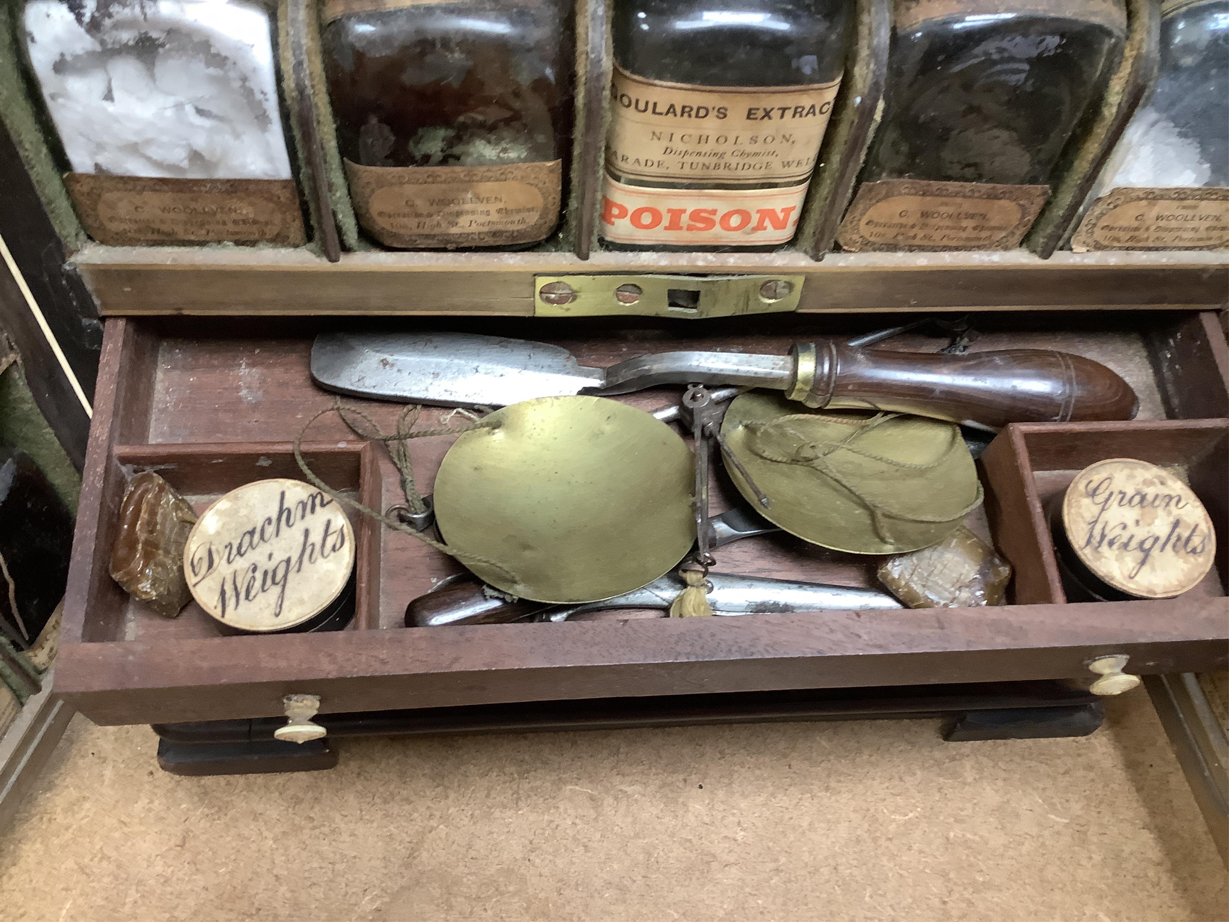 A 19th century mahogany apothecary cabinet, containing 20 bottles of various medicinal compounds and poisons, some sealed, all with paper labels, mainly for ‘C. Woollven, Operative & Dispensing Chemist, 108, High Street,